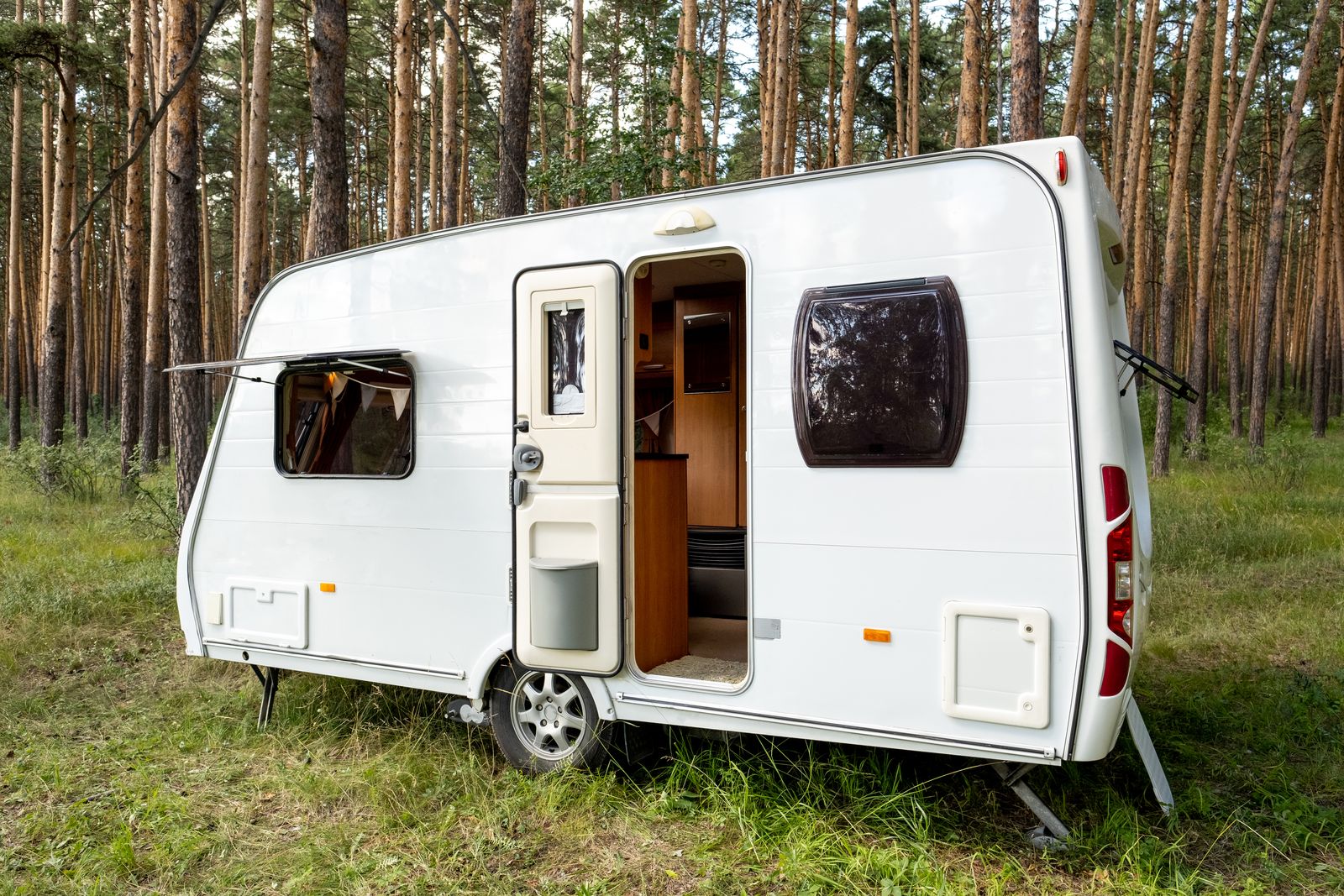 Abgestellter Wohnwagen mit ausgefahrenen Stützen und geöffneter Tür